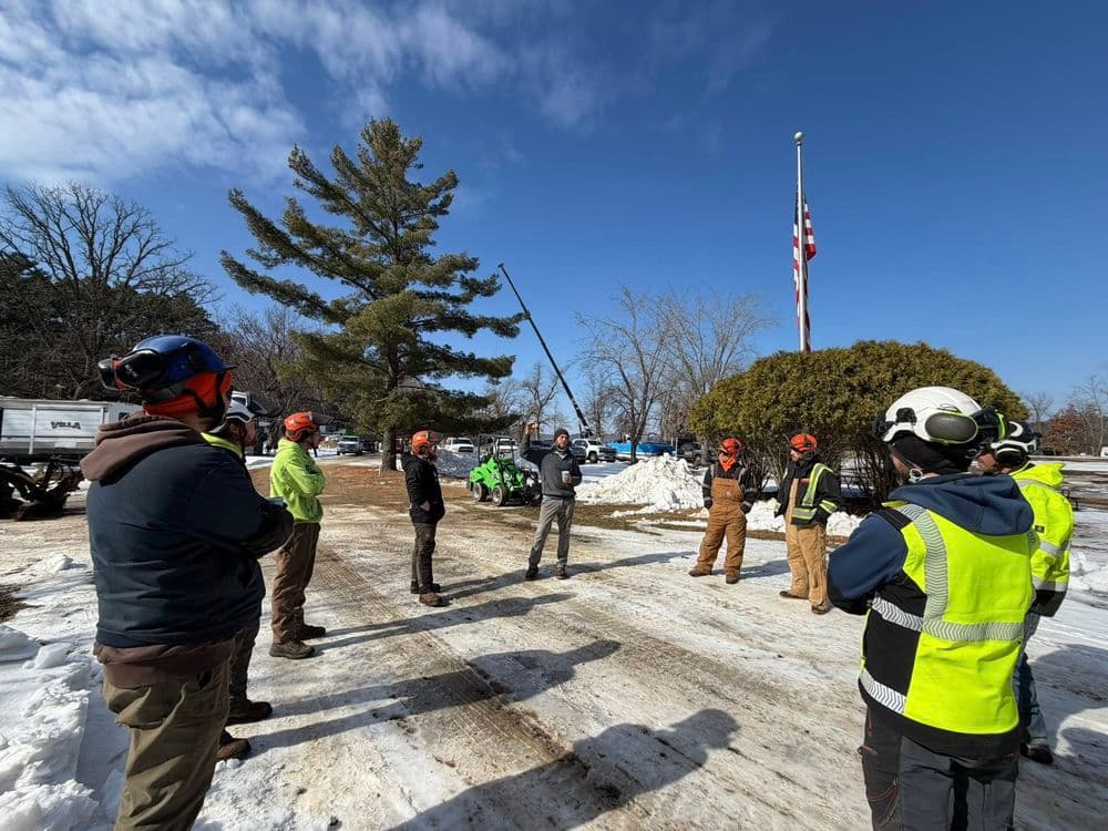 Construction workers in hard hats attend a safety briefing outdoors in winter conditions.