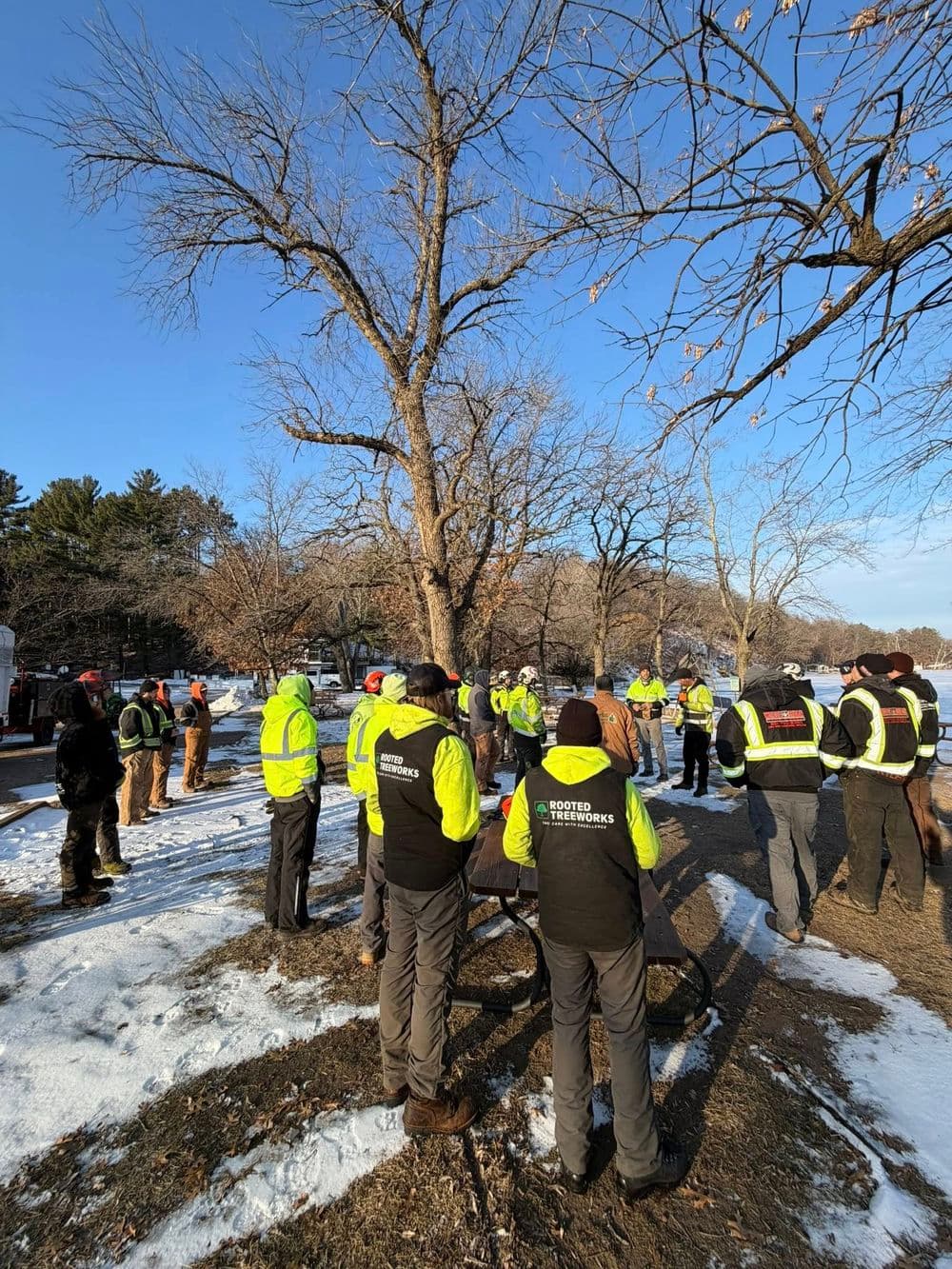 Group of workers in safety vests gathered outside for a training session in winter.
